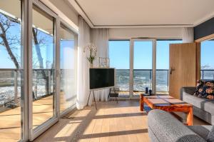 a living room with a television and large windows at Apartament Szafirowy z BEZPOŚREDNIM WIDOKIEM na morze- Nadmorski Luksus Apartamenty in Ustronie Morskie