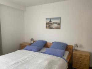 a bedroom with a bed with two blue pillows at Apartmenthaus am Watt Büsum in Büsum