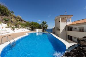 ein Pool neben einem Gebäude und einem Strand in der Unterkunft Fantasticas vistas al mar, playa y piscina in Radazul