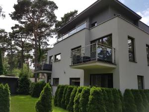 a white house with a balcony and bushes at Villa VIP Jurata in Jurata