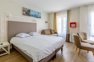 a hotel room with a large bed and chairs at Résidence Pierre & Vacances Le Palais des Gouverneurs in Saint-Martin-de-Ré