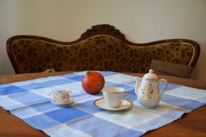 une table avec un tissu de table bleu et blanc avec une pomme et des tasses dans l'établissement Das Herrenhaus, à Kevelaer