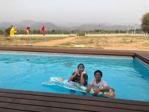 dos personas están sentadas en una piscina en ณ กาญโฮม, en Ban Hin Hak