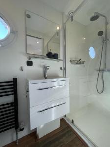 a white bathroom with a sink and a shower at Houseboat Kamperland in Kamperland