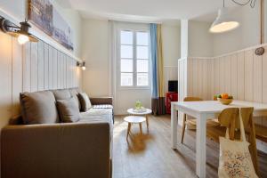 ein Wohnzimmer mit einem Sofa und einem Tisch in der Unterkunft Résidence Pierre & Vacances Le Palais des Gouverneurs in Saint-Martin-de-Ré