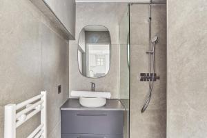 La salle de bains est pourvue d'un lavabo et d'un miroir. dans l'établissement Apartment Loft Père Lachaise by Studio prestige, à Paris