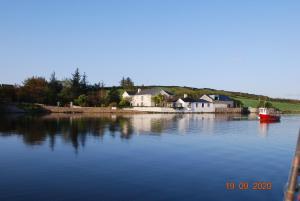a house on the shore of a lake with a boat at Seapoint House in Westport