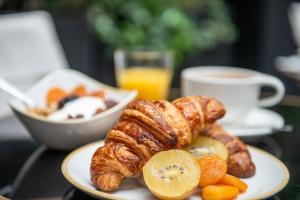 a plate of food with croissants and oranges on a table at Mom'Art Hotel in Paris