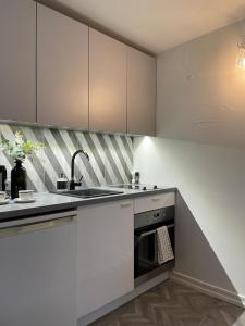 uma cozinha com armários brancos, um lavatório e um fogão em Linkuva Manor Apartment em Kaunas