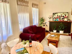 a living room with a red couch and a table at Rose End Cozy Apartment in Tumut