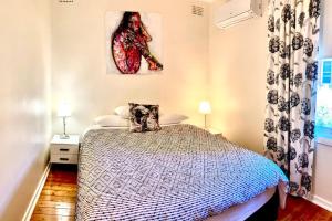 a bedroom with a bed and a painting on the wall at Rose End Cozy Apartment in Tumut