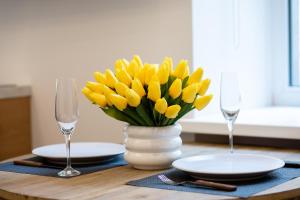 un vase de fleurs jaunes sur une table avec des verres dans l'établissement Brivibas House Design Apartments In City Center, à Riga