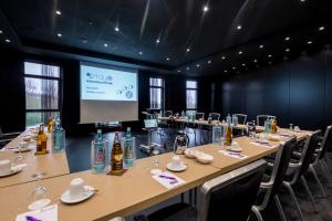 una habitación con una mesa larga con sillas y una pantalla en stays by friends Gelsenkirchen, en Gelsenkirchen