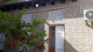 a brick building with a white door and a window at Barlos XVIII in Bukhara