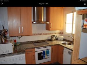- une cuisine avec des placards en bois, un évier et une cuisinière dans l'établissement Luxury two bed apartment with panoramic views, à Benalmádena
