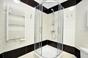ミエンジズドロイェにあるApartament Gryfa Pomorskiego Międzyzdrojeの黒と白のタイルを使用したバスルーム(ガラス張りのシャワー付)