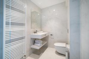 a white bathroom with a toilet and a sink at Miramare Hotel in Zadar
