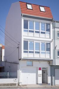 a white house with a red roof at Apartamentos pilucha in Muxia