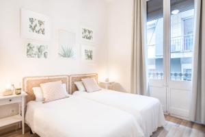2 camas en un dormitorio blanco con ventana en Gracia15 en Barcelona