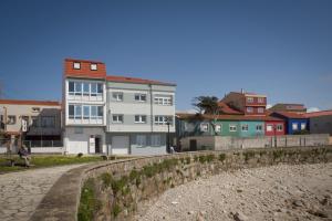 un grupo de edificios junto a una pared junto a una playa en Apartamentos pilucha, en Muxía