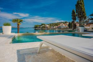 a pool with a white bench and a view of the water at House with pool by the sea - Dugi otok, Žman in Žman