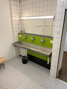 a bathroom with green and white tiles and a mirror at HoStel Self Check-In Solothurn in Zuchwil