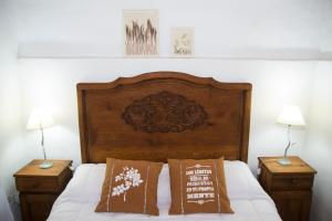 1 cama con cabecero de madera y 2 mesitas de noche en Cabañas Los 2 Algarrobos, en Santa Rosa de Calamuchita