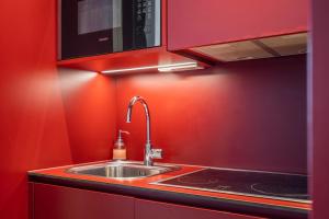 eine Küche mit einem Waschbecken und einer roten Wand in der Unterkunft easy flat Green Prater in Wien
