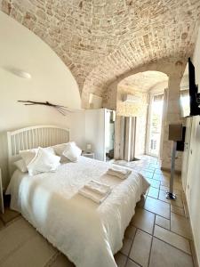 1 dormitorio con 1 cama blanca grande y techo de piedra en Il Nido, en Castellana Grotte