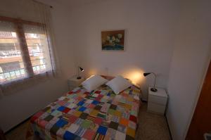 a bedroom with a colorful bed and a window at Mare Nostrum 223 in Torroella de Montgrí