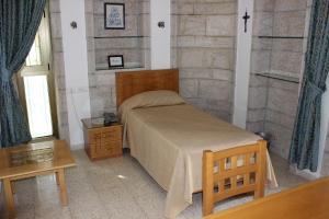 a bedroom with a bed with a wooden headboard and a table at The Bridgettine Sisters Monastery in Jerusalem