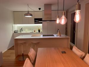 eine Küche mit einem Holztisch und einigen Lampen in der Unterkunft Alva Luxury Flat in Matosinhos