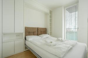 białe łóżko w białym pokoju z oknem w obiekcie easy flat Green Prater w Wiedniu
