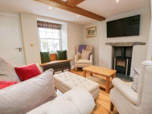 a living room with white furniture and a flat screen tv at Jessamine Cottage in Ambleside