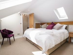 a bedroom with a large white bed with purple pillows at Jessamine Cottage in Ambleside