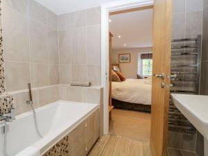 a bathroom with a bath tub and a bedroom at Jessamine Cottage in Ambleside +19 photos