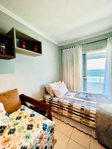 - une chambre avec un lit, une chaise et une fenêtre dans l'établissement AP alto padrão, frente mar panorâmico., à Praia Grande
