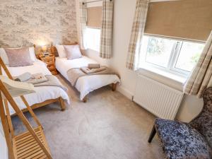 a small bedroom with two beds and a chair at Rose Dene in Brough