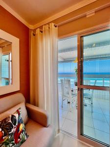 - un salon avec un canapé et une porte coulissante en verre dans l'établissement AP alto padrão, frente mar panorâmico., à Praia Grande