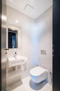 a white bathroom with a toilet and a sink at Miramare Hotel in Zadar