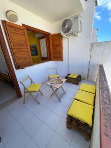 a balcony with yellow chairs and a table and chairs at Appartamento Girasole in San Vito lo Capo