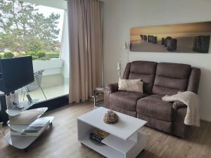a living room with a brown couch and a tv at Scharbeutz, 1 Raum Fewo mit sonnigem Balkon, ruhig und zentral in Scharbeutz