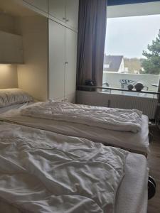 two unmade beds in a bedroom with a window at Scharbeutz, 1 Raum Fewo mit sonnigem Balkon, ruhig und zentral in Scharbeutz