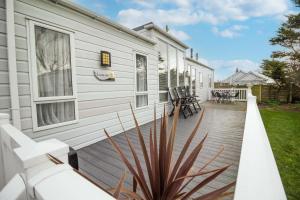 een houten terras naast een wit huis bij Luxury Caravan With Decking Nearby Scratby Beach In Norfolk Ref 50001bm in Great Yarmouth
