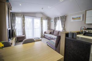 een woonkamer met een bank en een tafel bij Luxury Caravan With Decking Nearby Scratby Beach In Norfolk Ref 50001bm in Great Yarmouth