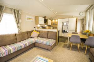 een woonkamer met een bank en een tafel en een keuken bij Luxury Caravan With Decking Nearby Scratby Beach In Norfolk Ref 50001bm in Great Yarmouth