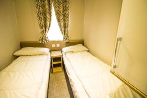 twee bedden in een kleine kamer met een raam bij Luxury Caravan With Decking Nearby Scratby Beach In Norfolk Ref 50001bm in Great Yarmouth