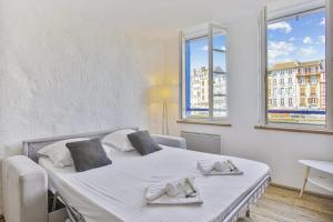 a white bedroom with a bed with two towels on it at Flat with typical charm and terrace - Bayonne - Welkeys in Bayonne