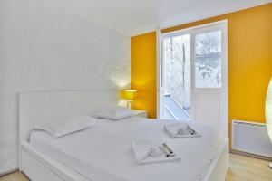 - un lit blanc dans une chambre avec fenêtre dans l'établissement Flat with typical charm and terrace - Bayonne - Welkeys, à Bayonne