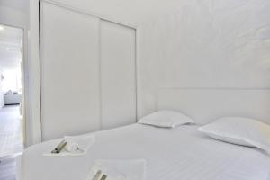 - une chambre blanche avec un lit et un miroir dans l'établissement Flat with typical charm and terrace - Bayonne - Welkeys, à Bayonne